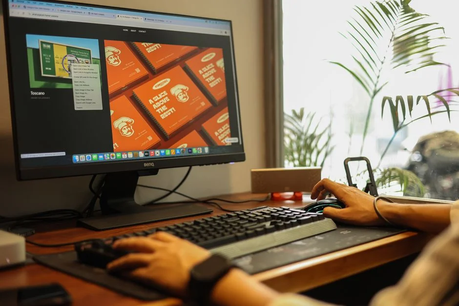 Man working on web design at home office setup with dual monitors.